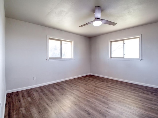 empty room with a healthy amount of sunlight, ceiling fan, baseboards, and wood finished floors