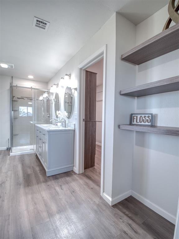 full bathroom with vanity, wood finished floors, visible vents, and a shower stall