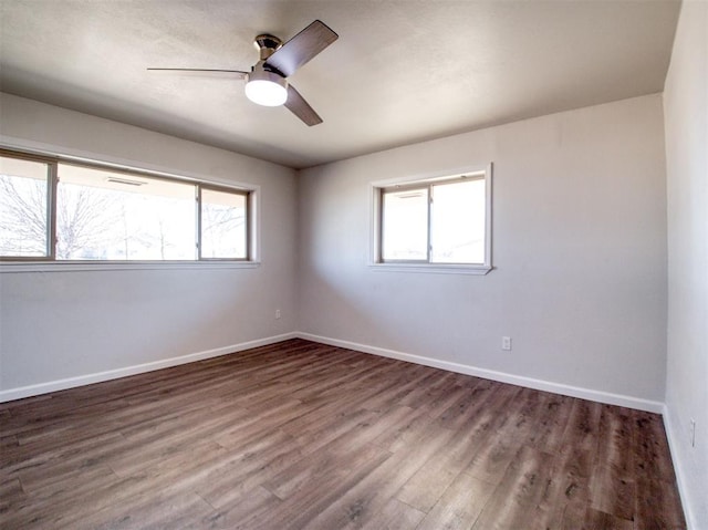 empty room featuring a ceiling fan, baseboards, a wealth of natural light, and wood finished floors