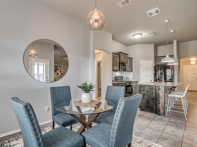 dining room featuring arched walkways, visible vents, and baseboards