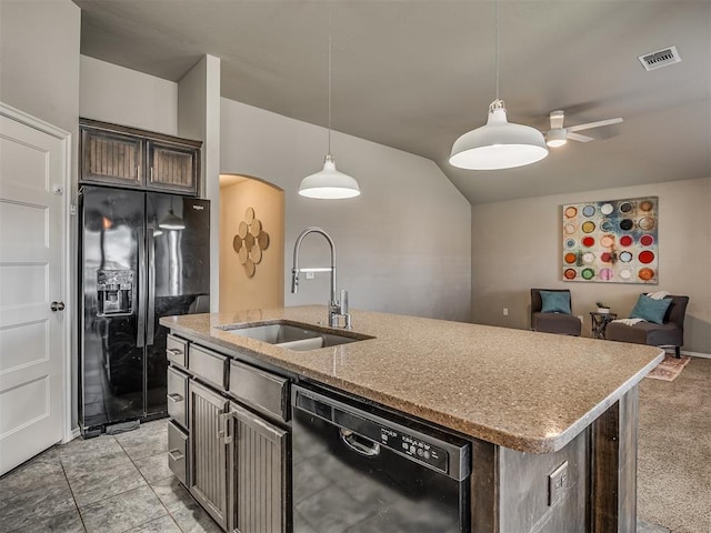 kitchen with visible vents, decorative light fixtures, a kitchen island with sink, black appliances, and a sink