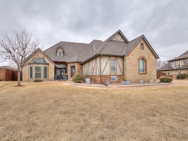 view of front of property featuring stone siding, roof with shingles, a front lawn, and stucco siding