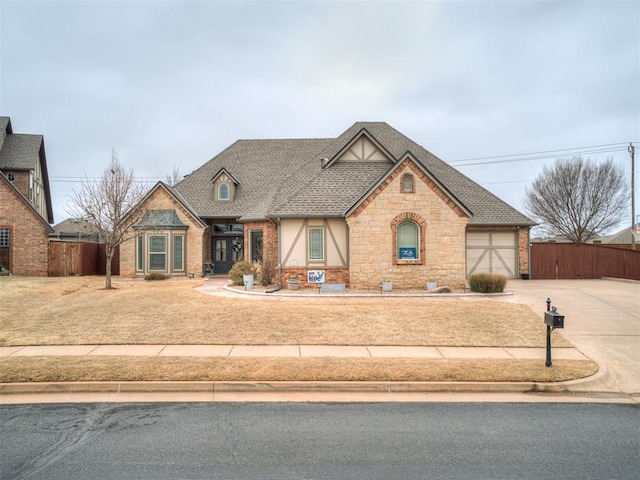 view of front of house featuring a garage, driveway, a shingled roof, and fence