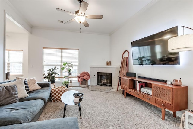 carpeted living room featuring ornamental molding, a tile fireplace, visible vents, and a ceiling fan