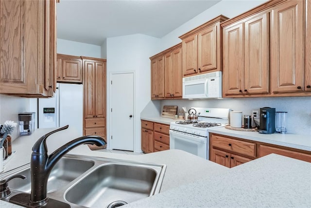 kitchen featuring white appliances, light countertops, and a sink