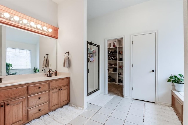 bathroom featuring a shower stall, double vanity, a sink, and tile patterned floors