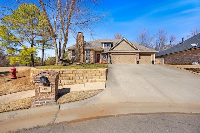 traditional-style house featuring a chimney, concrete driveway, and an attached garage