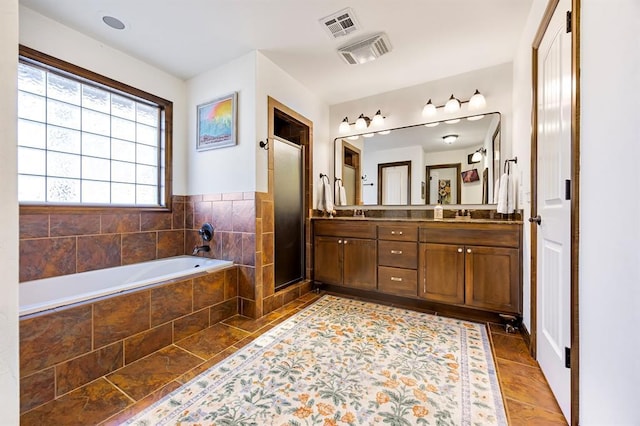 full bath featuring visible vents, a stall shower, a garden tub, and double vanity