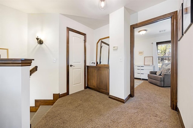 corridor featuring baseboards, an upstairs landing, and carpet flooring