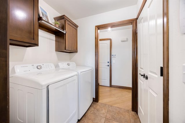 laundry area featuring washing machine and clothes dryer, cabinet space, baseboards, and light tile patterned flooring