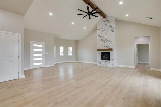 unfurnished living room featuring beam ceiling, visible vents, a premium fireplace, ceiling fan, and light wood-type flooring