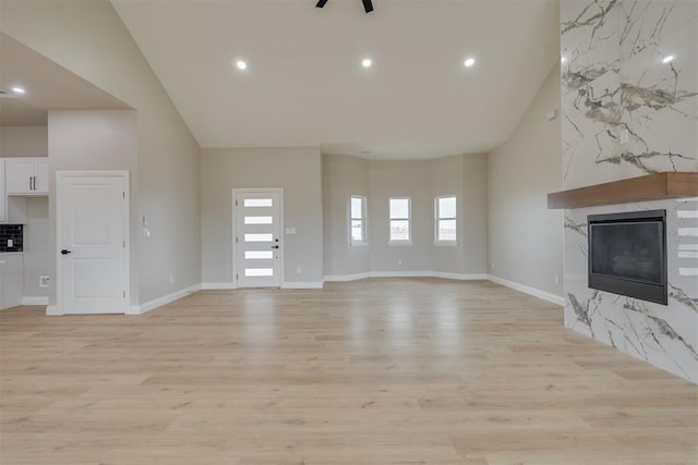 unfurnished living room with light wood-style flooring, recessed lighting, a high end fireplace, and baseboards