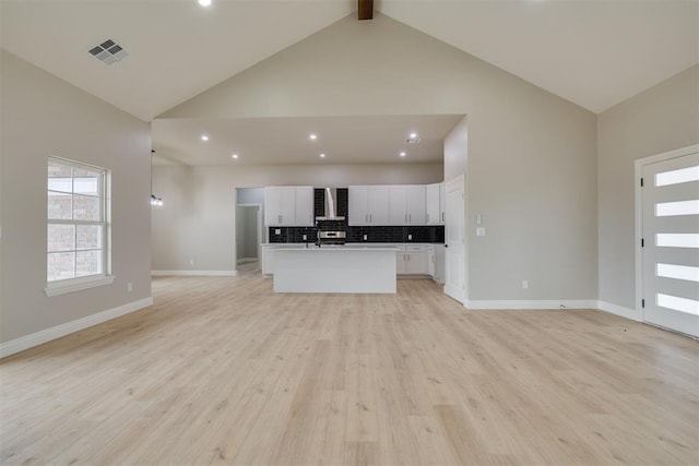 unfurnished living room featuring high vaulted ceiling, visible vents, baseboards, light wood-style floors, and beam ceiling