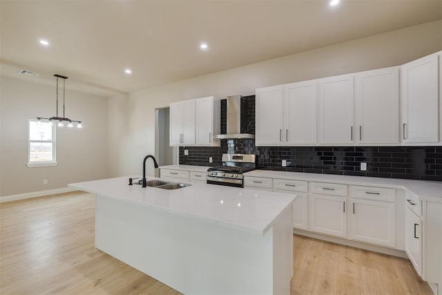 kitchen with visible vents, decorative backsplash, wall chimney exhaust hood, a sink, and gas stove