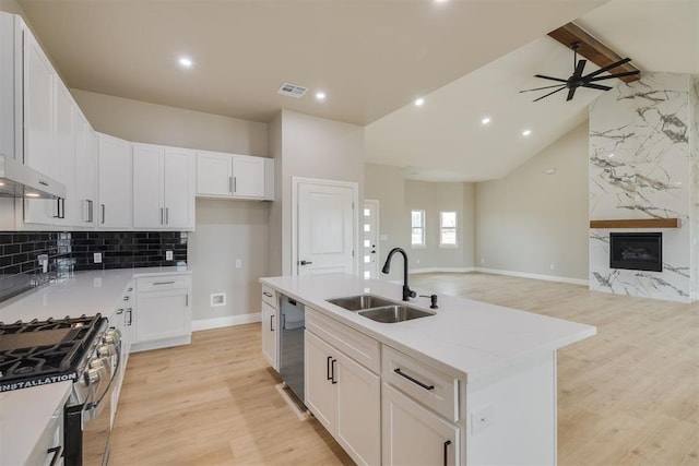 kitchen with visible vents, dishwashing machine, a premium fireplace, open floor plan, and a sink