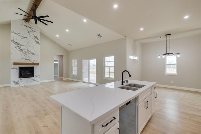 kitchen with a kitchen island with sink, a fireplace, a sink, open floor plan, and dishwasher