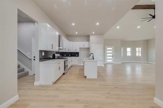 kitchen featuring range with gas cooktop, decorative backsplash, open floor plan, white cabinetry, and light wood-type flooring