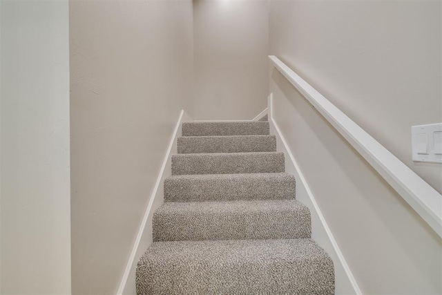 staircase featuring carpet flooring and baseboards