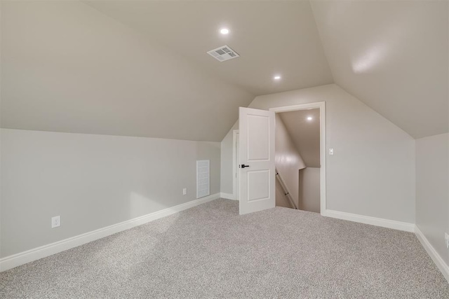 additional living space with carpet flooring, visible vents, vaulted ceiling, and baseboards