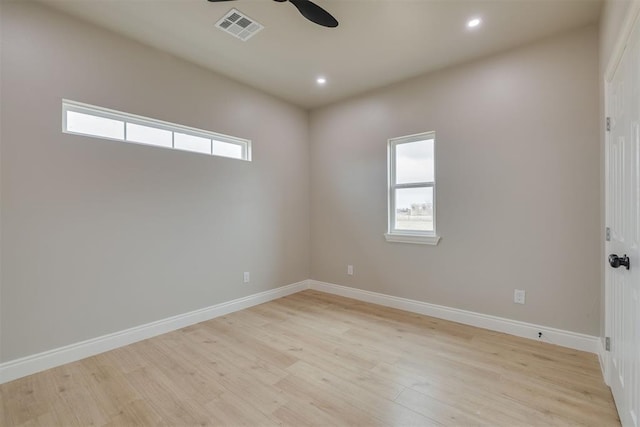 spare room featuring light wood finished floors, baseboards, visible vents, and a ceiling fan