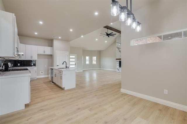 kitchen with light wood-type flooring, ceiling fan, decorative backsplash, and a sink