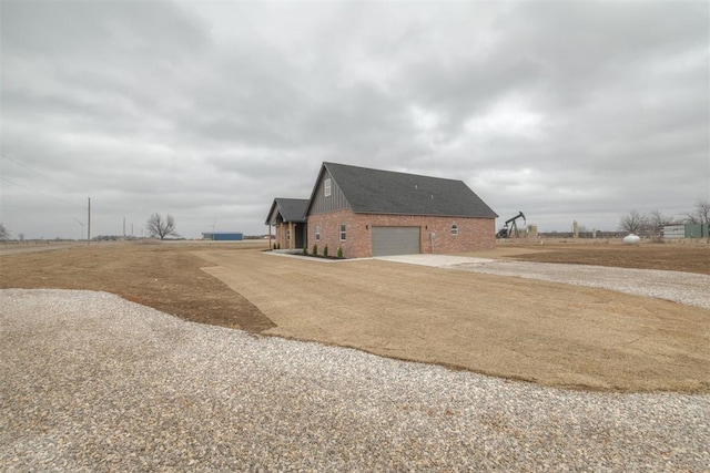 view of home's exterior with board and batten siding, brick siding, and driveway