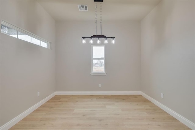 unfurnished room featuring a wealth of natural light, light wood-style flooring, visible vents, and baseboards