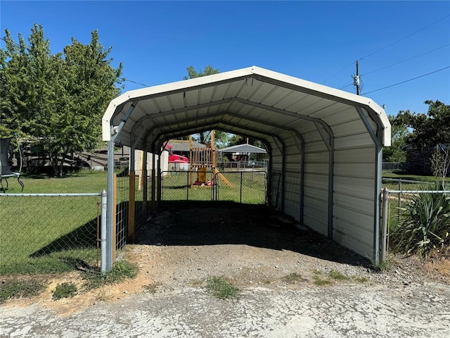 view of parking with a trampoline, fence, and a detached carport