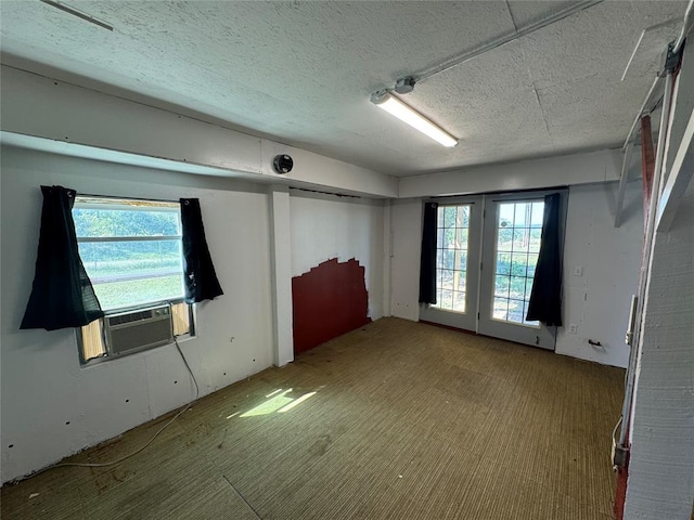 unfurnished room featuring light carpet, a textured ceiling, and cooling unit