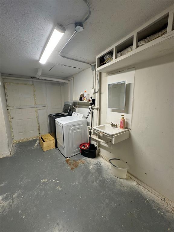 unfinished below grade area with a sink, a textured ceiling, and separate washer and dryer