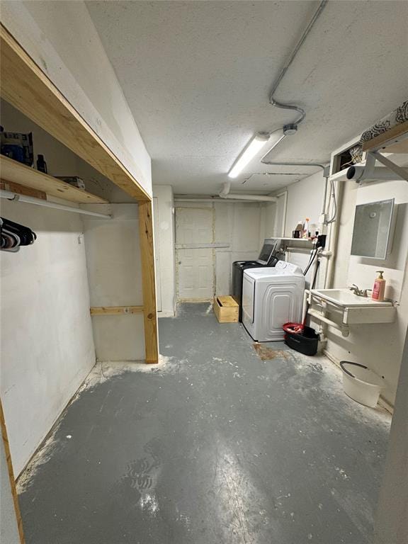 below grade area featuring a textured ceiling, a sink, and independent washer and dryer