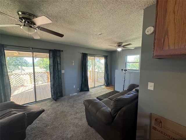 carpeted living room with a textured ceiling, ceiling fan, and visible vents