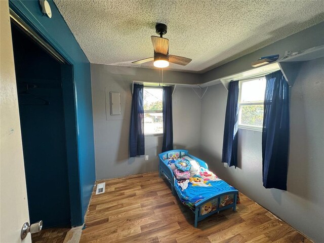 bedroom featuring a textured ceiling, multiple windows, wood finished floors, and visible vents