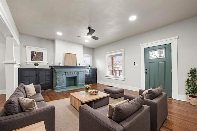 living room featuring a fireplace with flush hearth, baseboards, wood finished floors, and recessed lighting