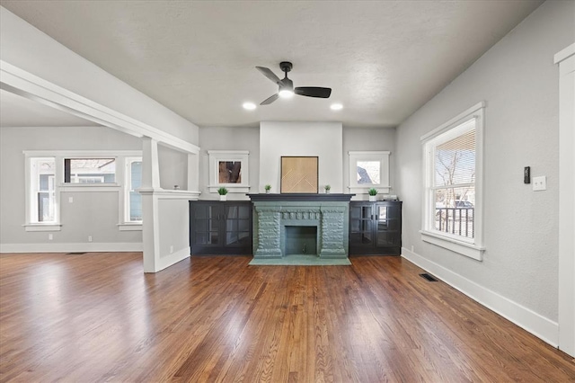 unfurnished living room with a fireplace with flush hearth, visible vents, dark wood-type flooring, and baseboards