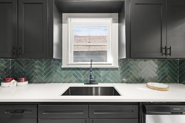 kitchen featuring gray cabinetry, a sink, light countertops, dishwasher, and tasteful backsplash