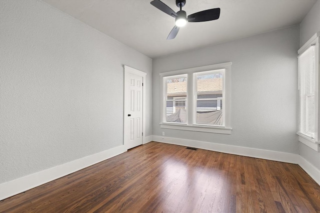 unfurnished room with ceiling fan, wood finished floors, visible vents, and baseboards