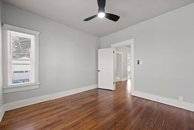 unfurnished room with ceiling fan, baseboards, and dark wood-type flooring