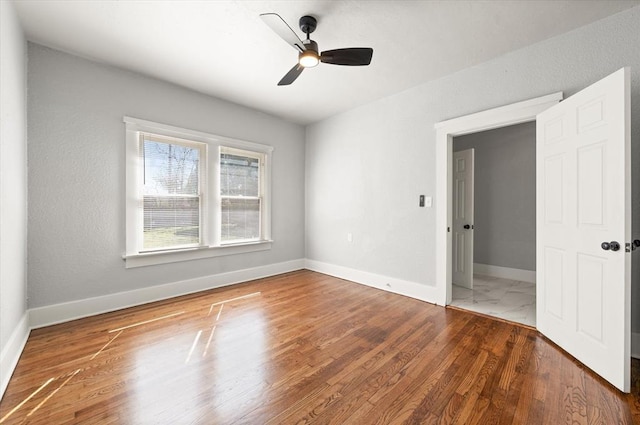 spare room featuring a ceiling fan, baseboards, and wood finished floors