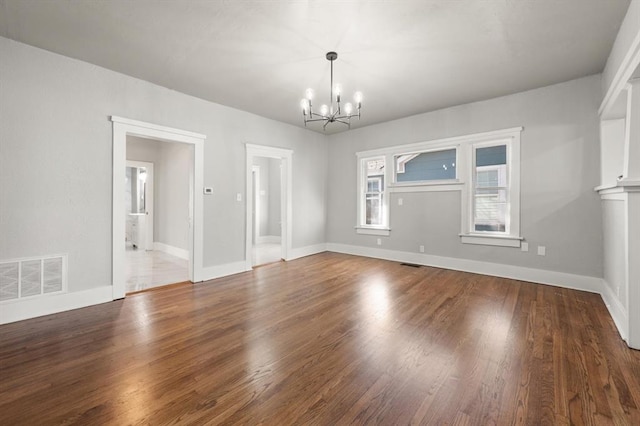 interior space featuring wood finished floors, visible vents, baseboards, and an inviting chandelier