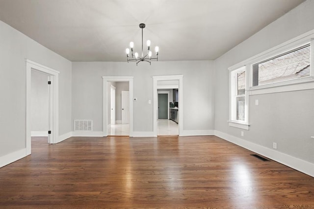 unfurnished dining area with visible vents, an inviting chandelier, and wood finished floors