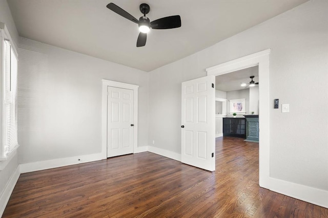 unfurnished room with dark wood-style floors, baseboards, and a ceiling fan