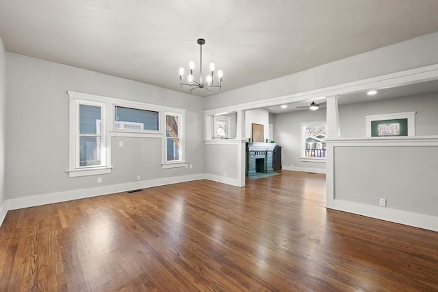 unfurnished living room with a brick fireplace, wood finished floors, visible vents, and baseboards