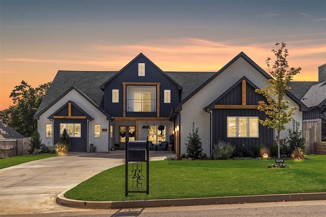 modern inspired farmhouse featuring board and batten siding, concrete driveway, a lawn, and a shingled roof