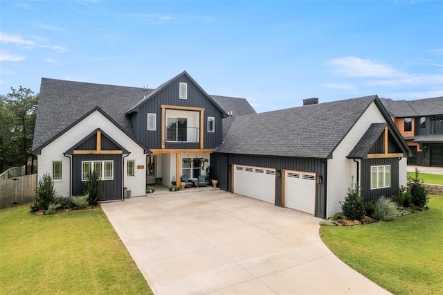 modern farmhouse featuring a garage, driveway, a shingled roof, and a front yard