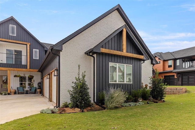 exterior space with a garage, concrete driveway, a front lawn, board and batten siding, and brick siding