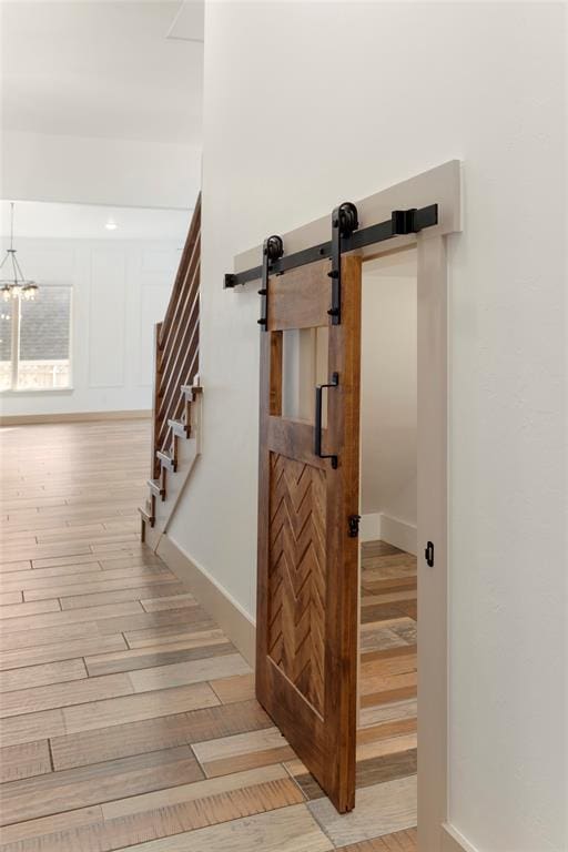 staircase featuring a barn door, baseboards, and wood finished floors