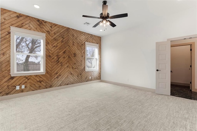 carpeted spare room with baseboards, wooden walls, visible vents, and recessed lighting