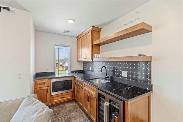 kitchen featuring wine cooler, a sink, open shelves, stainless steel microwave, and dark stone countertops