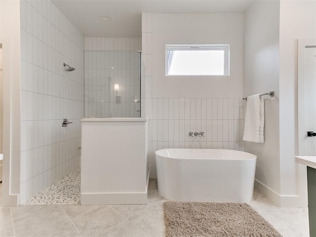 bathroom featuring a freestanding tub, tile patterned flooring, a walk in shower, and tile walls